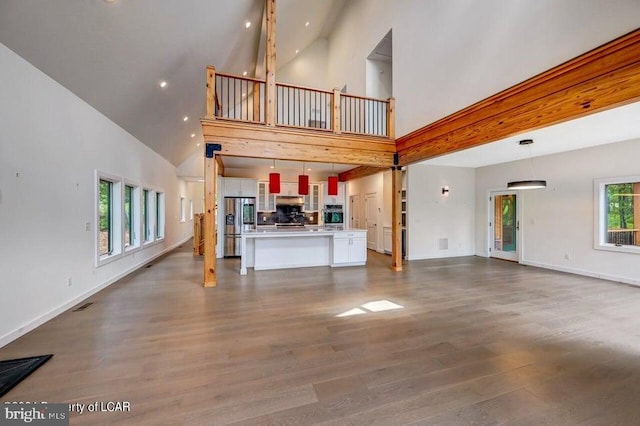 unfurnished living room featuring wood-type flooring and high vaulted ceiling