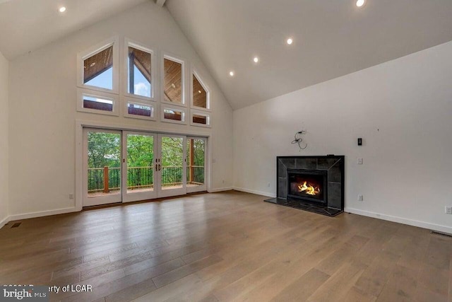 unfurnished living room with high vaulted ceiling, a high end fireplace, and hardwood / wood-style floors