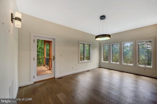 unfurnished dining area featuring plenty of natural light and dark hardwood / wood-style flooring