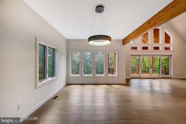 unfurnished living room with vaulted ceiling with beams, dark wood-type flooring, and a healthy amount of sunlight