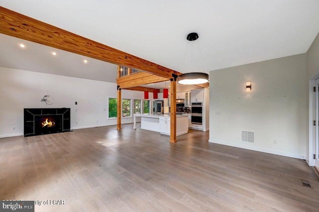 unfurnished living room with hardwood / wood-style flooring, sink, lofted ceiling with beams, and a tile fireplace