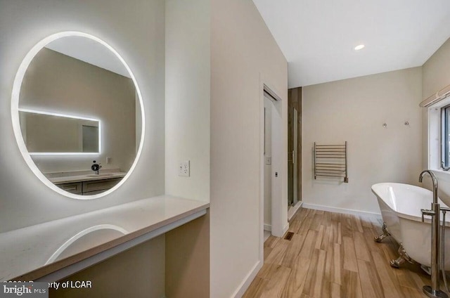 bathroom with vanity, hardwood / wood-style floors, and a tub to relax in