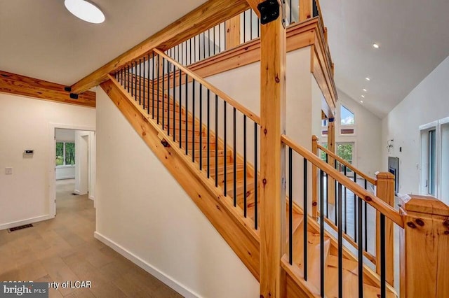 stairway featuring beamed ceiling, wood-type flooring, and high vaulted ceiling