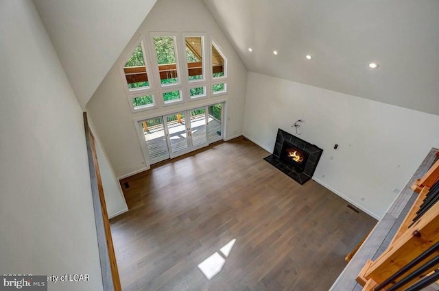 unfurnished living room with a high end fireplace, dark hardwood / wood-style flooring, and high vaulted ceiling