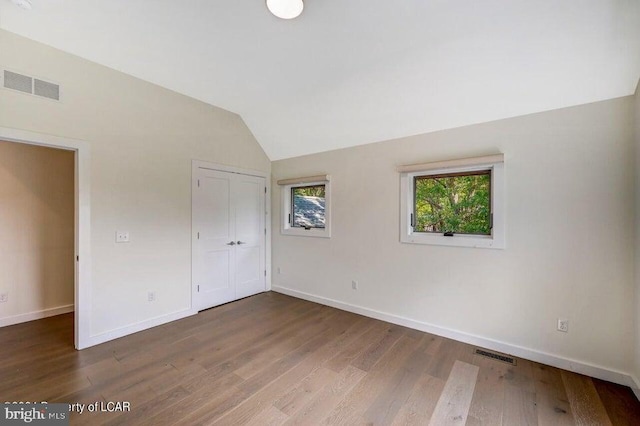 unfurnished bedroom featuring a closet, lofted ceiling, and wood-type flooring