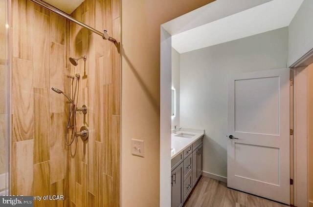 bathroom featuring vanity, wood-type flooring, and a tile shower