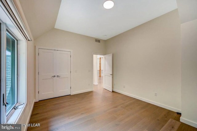 unfurnished bedroom featuring lofted ceiling and light hardwood / wood-style flooring