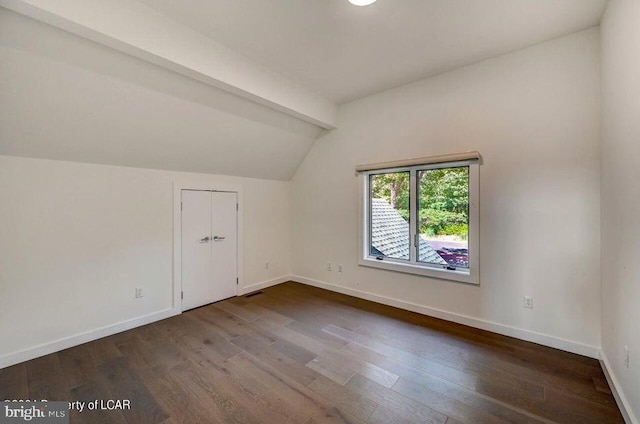 additional living space featuring dark wood-type flooring and lofted ceiling with beams