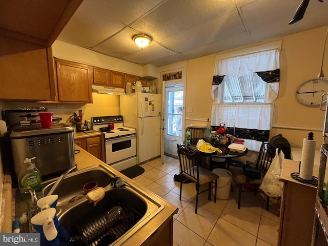 kitchen with sink, a paneled ceiling, white appliances, and light tile patterned floors