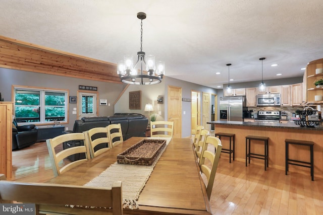 dining space featuring a notable chandelier, a textured ceiling, and light wood-type flooring