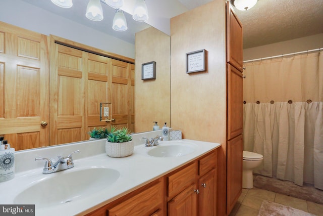 bathroom featuring vanity, toilet, tile patterned flooring, and a textured ceiling