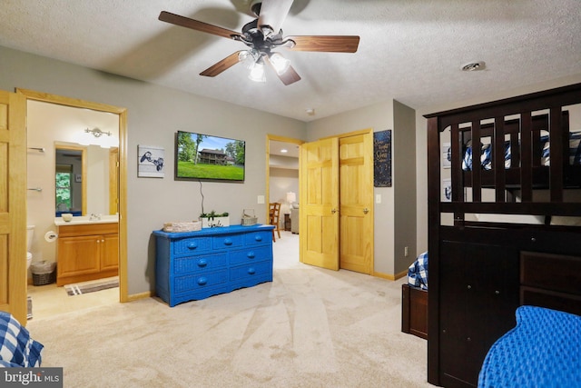 bedroom with sink, ensuite bath, light colored carpet, a textured ceiling, and ceiling fan