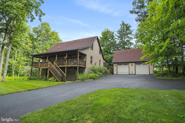 view of front of home featuring a garage, a wooden deck, an outdoor structure, and a front lawn