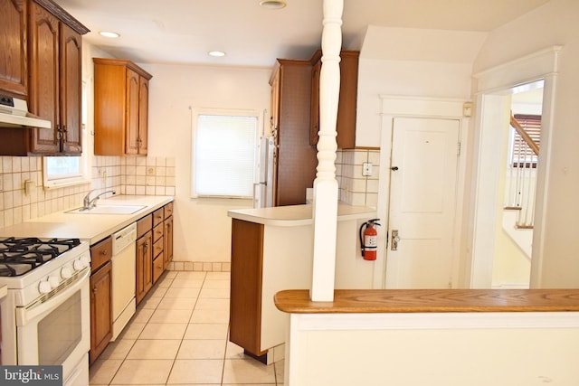 kitchen featuring sink, light tile patterned floors, backsplash, and white appliances