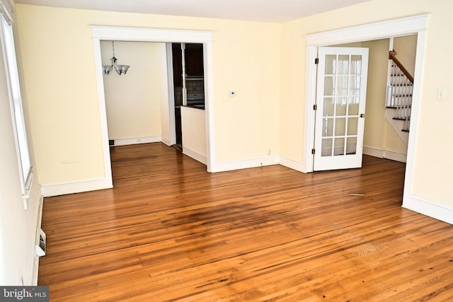 empty room with wood-type flooring and a chandelier