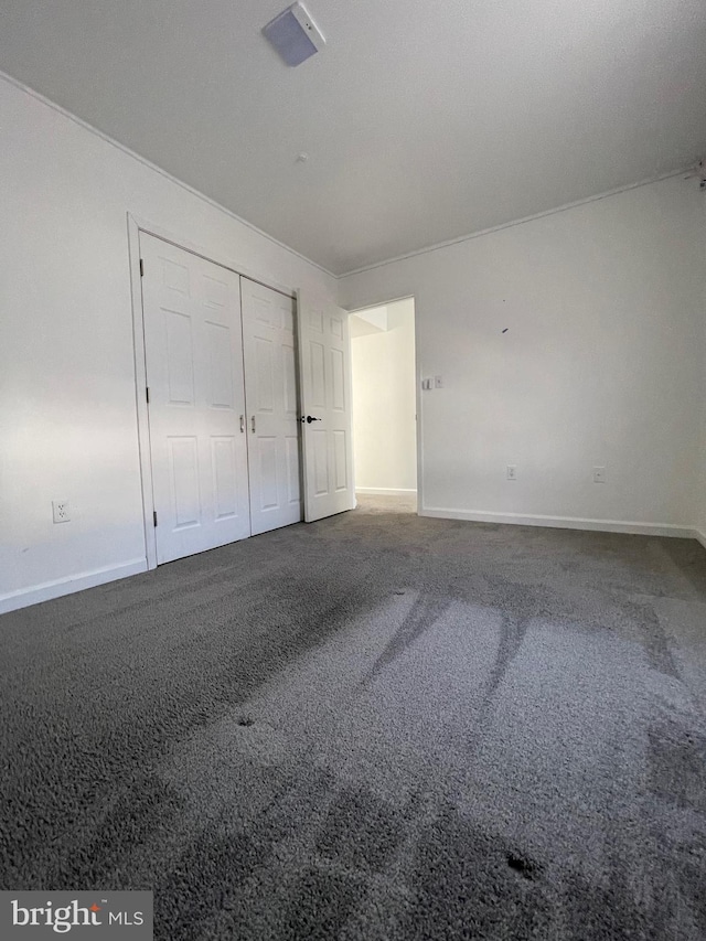 unfurnished bedroom featuring a closet, baseboards, and carpet floors