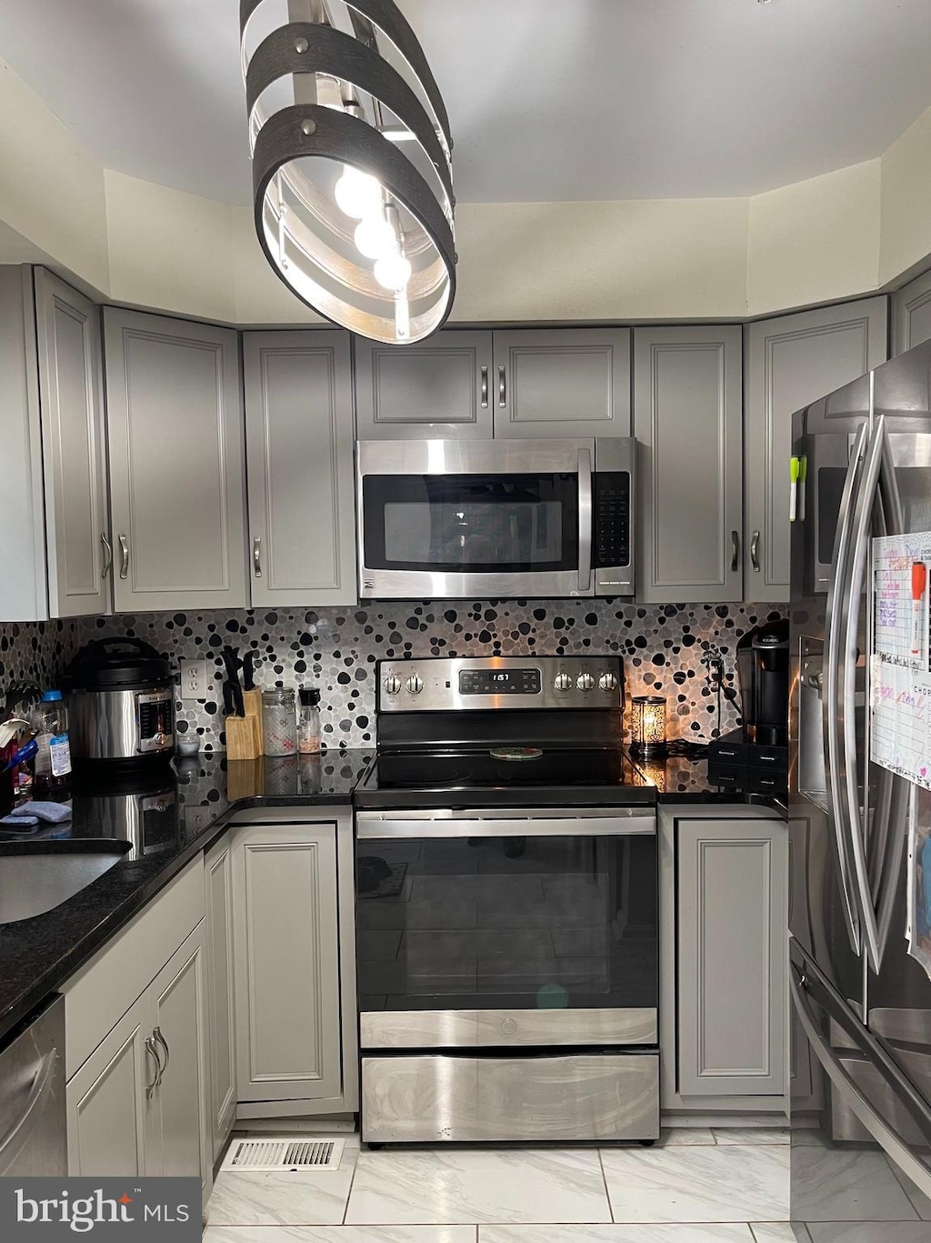 kitchen with sink, gray cabinets, dark stone countertops, backsplash, and stainless steel appliances