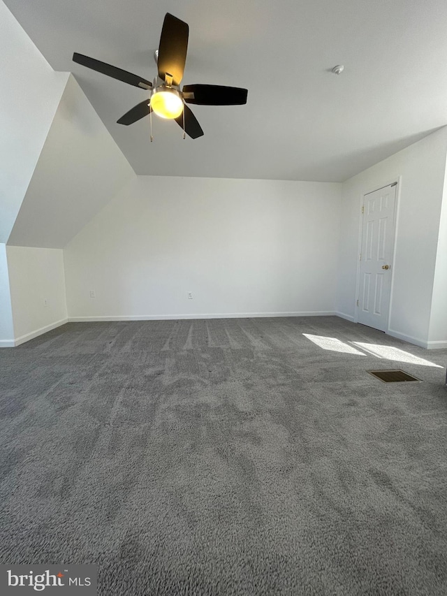 additional living space featuring baseboards, dark carpet, and vaulted ceiling