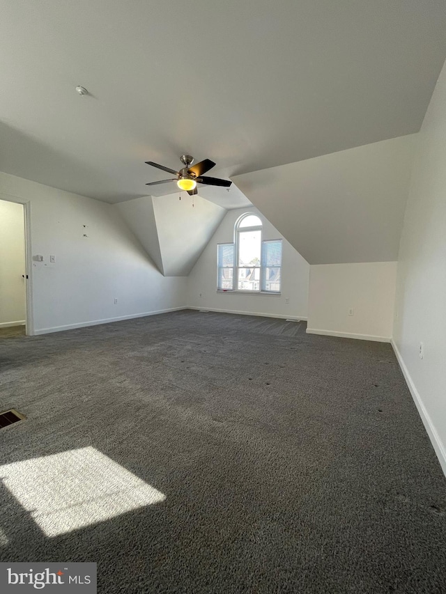 bonus room featuring visible vents, a ceiling fan, dark colored carpet, baseboards, and vaulted ceiling