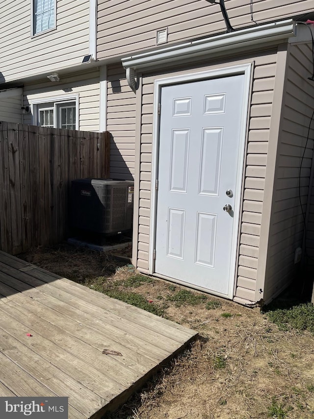 doorway to property with cooling unit and fence