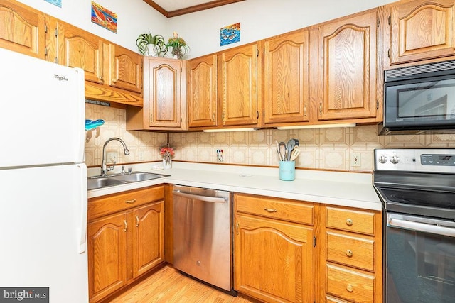 kitchen with sink, decorative backsplash, stainless steel appliances, and light wood-type flooring