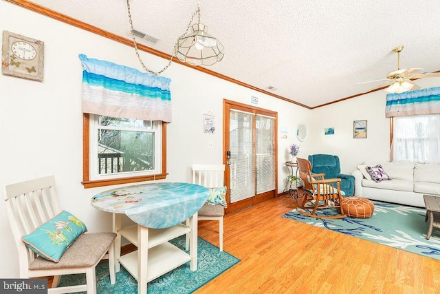 interior space with lofted ceiling, wood-type flooring, ornamental molding, and a textured ceiling