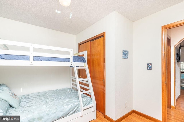 bedroom with a closet, light hardwood / wood-style flooring, and a textured ceiling