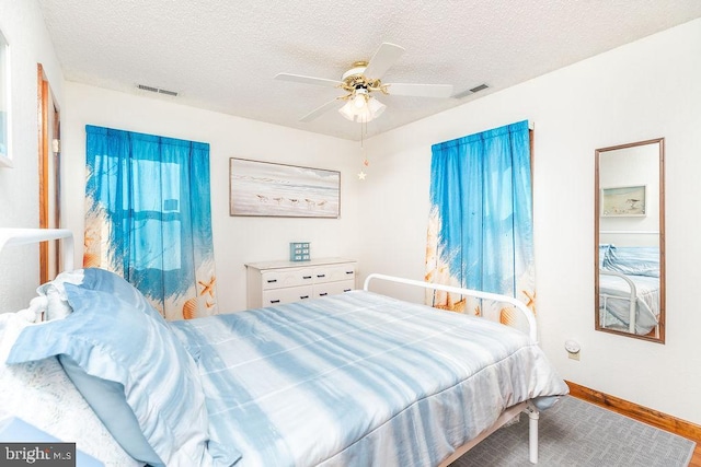 bedroom with ceiling fan, hardwood / wood-style floors, and a textured ceiling