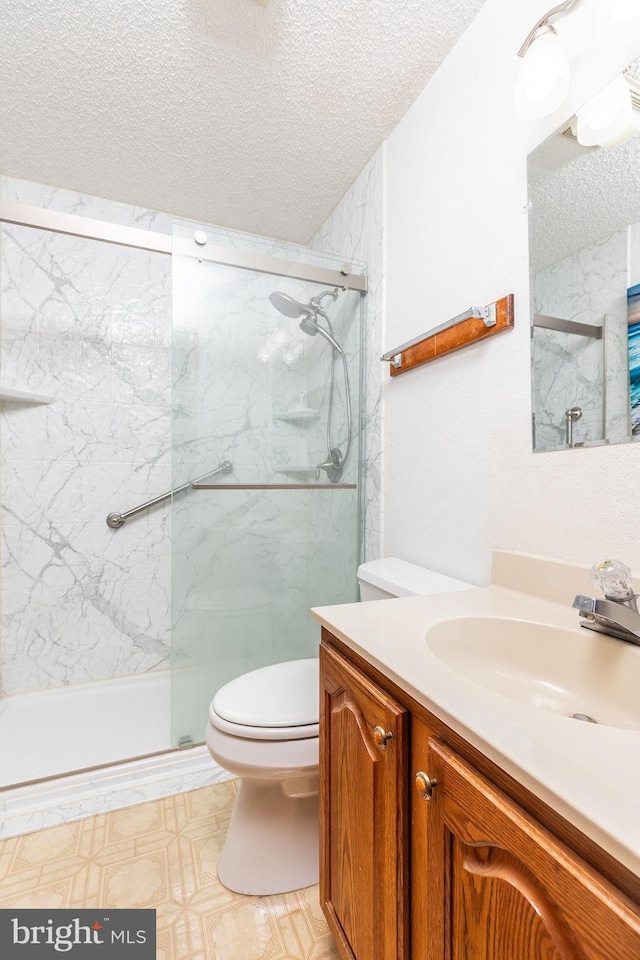 bathroom featuring walk in shower, vanity, toilet, and a textured ceiling