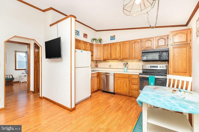 kitchen featuring crown molding, appliances with stainless steel finishes, light hardwood / wood-style floors, decorative backsplash, and vaulted ceiling