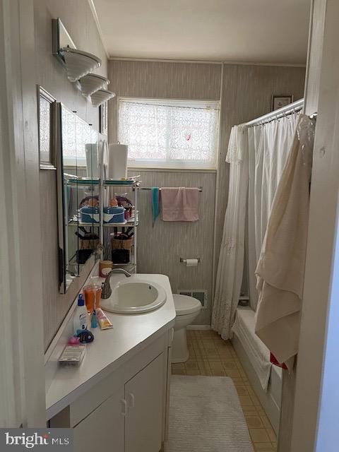 full bathroom with tile patterned floors, toilet, wood walls, vanity, and shower / bathtub combination with curtain