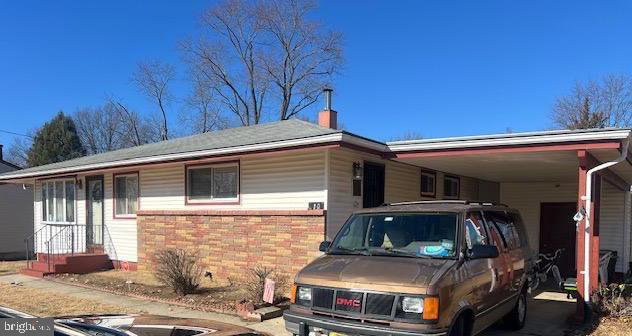 view of front facade featuring an attached carport, brick siding, and a chimney