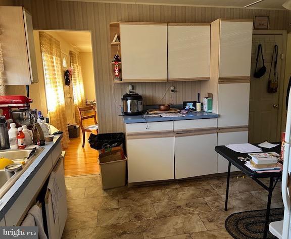 kitchen featuring a sink, open shelves, white cabinets, and stone finish floor