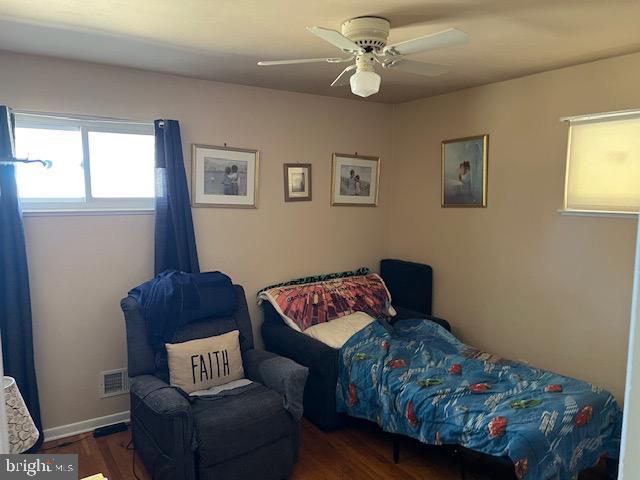 bedroom featuring visible vents, a ceiling fan, baseboards, and wood finished floors