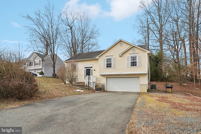 view of front of home with an attached garage, aphalt driveway, and cooling unit