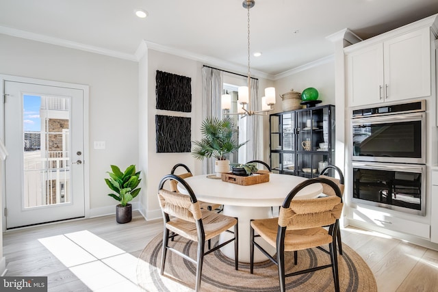 dining area with ornamental molding, a notable chandelier, light wood-style flooring, and baseboards