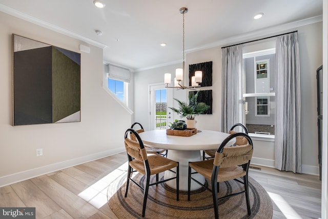 dining area featuring ornamental molding, light hardwood / wood-style floors, and a notable chandelier