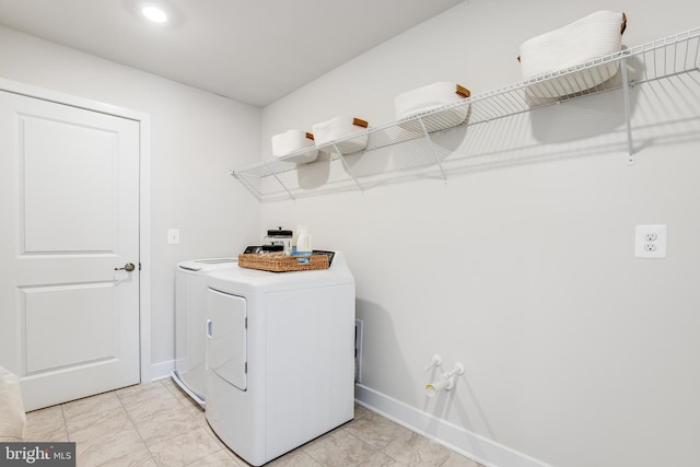 clothes washing area featuring baseboards, laundry area, and washer and dryer