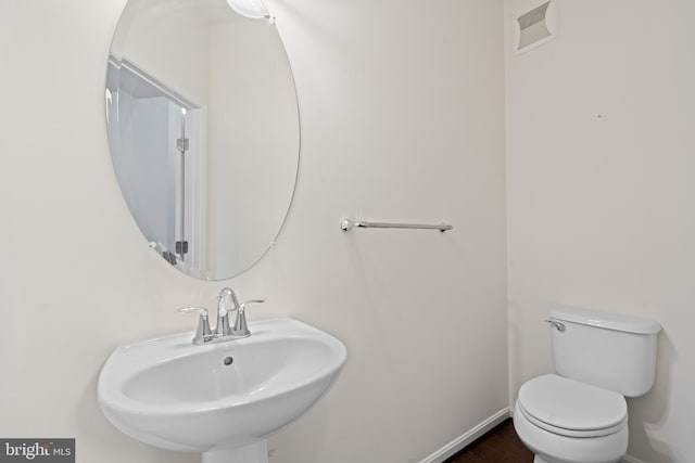 bathroom featuring visible vents, a sink, toilet, and baseboards