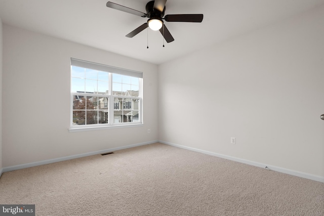 carpeted spare room with a ceiling fan, visible vents, and baseboards