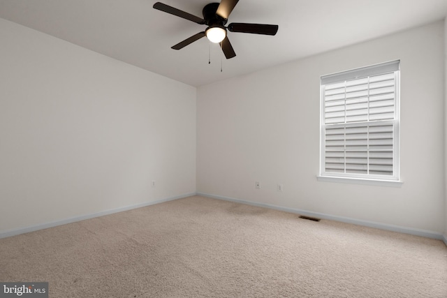 unfurnished room with carpet floors, visible vents, baseboards, and a ceiling fan