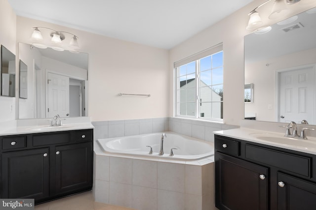 full bath with a garden tub, visible vents, two vanities, and a sink