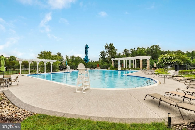 community pool with a patio area, fence, and a pergola