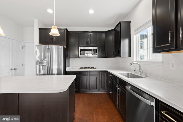 kitchen with decorative light fixtures, stainless steel appliances, light countertops, dark wood-type flooring, and a sink