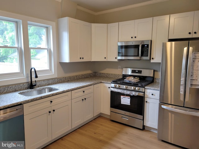 kitchen featuring a sink, appliances with stainless steel finishes, white cabinets, and ornamental molding