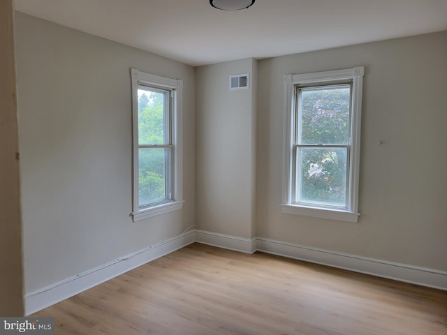 empty room with baseboards, visible vents, and light wood-style floors