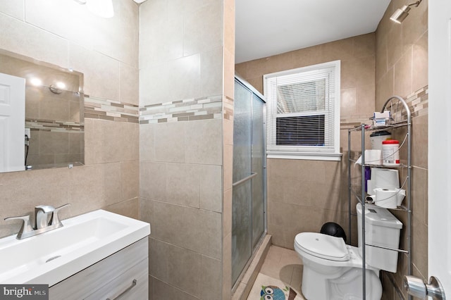 bathroom with vanity, toilet, tile walls, and walk in shower