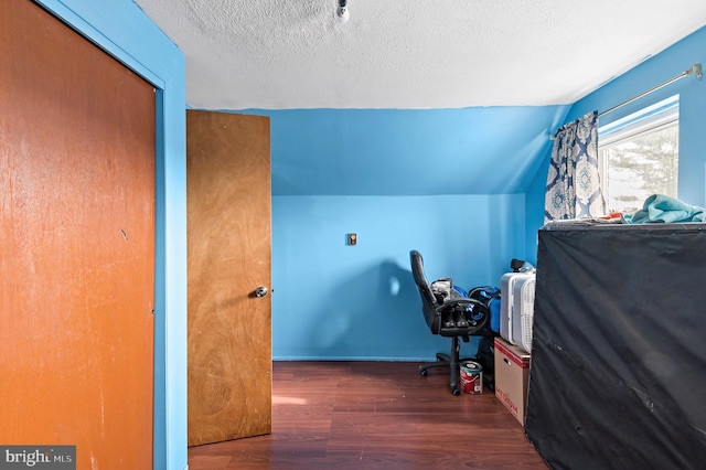 bedroom with lofted ceiling, dark wood-type flooring, and a textured ceiling