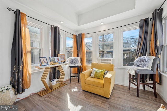 sitting room with a raised ceiling and light hardwood / wood-style flooring