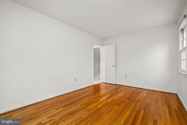 empty room with baseboards and hardwood / wood-style flooring